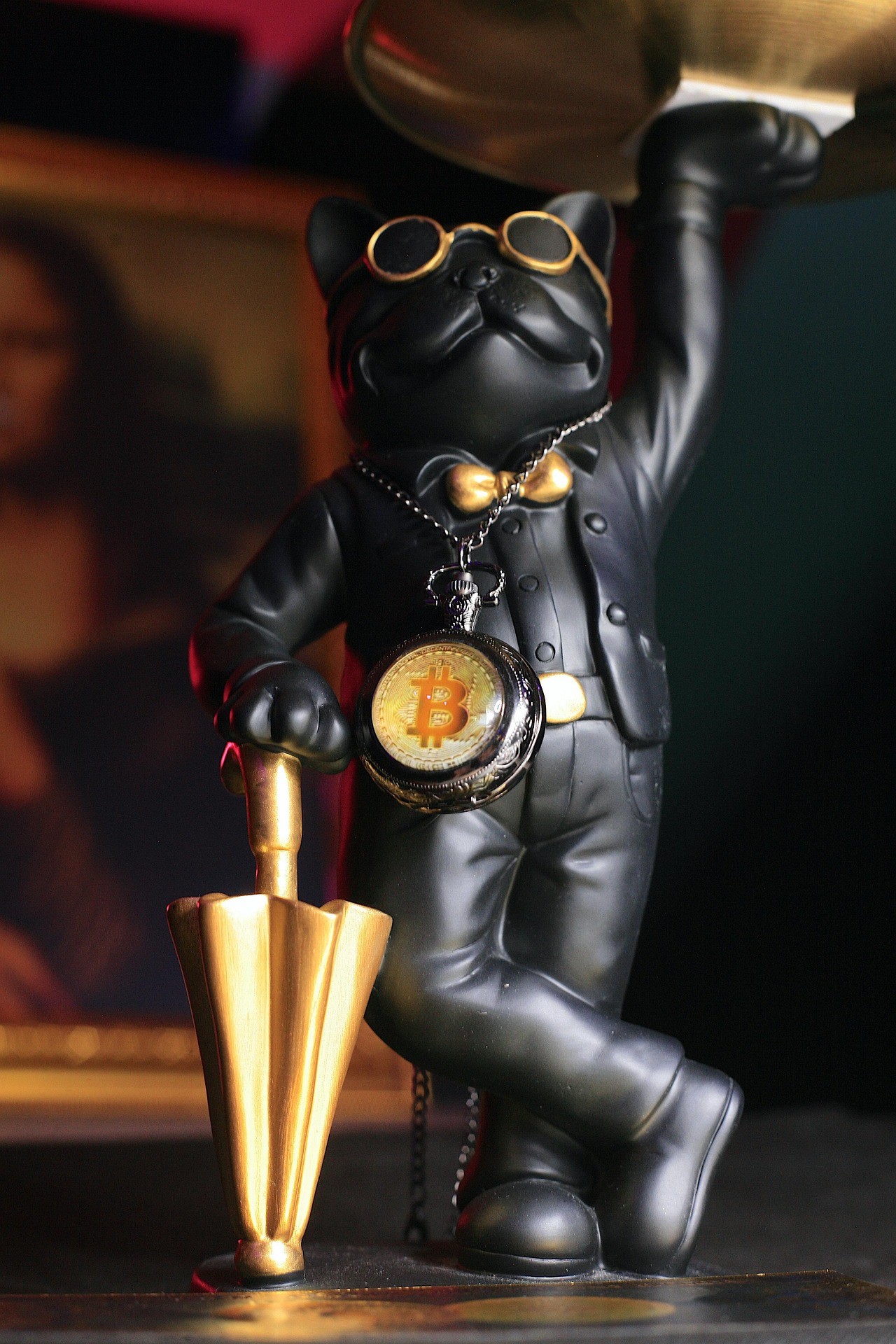 A black figurine of a French bulldog wearing sunglasses, a gold bow tie, and a suit.
